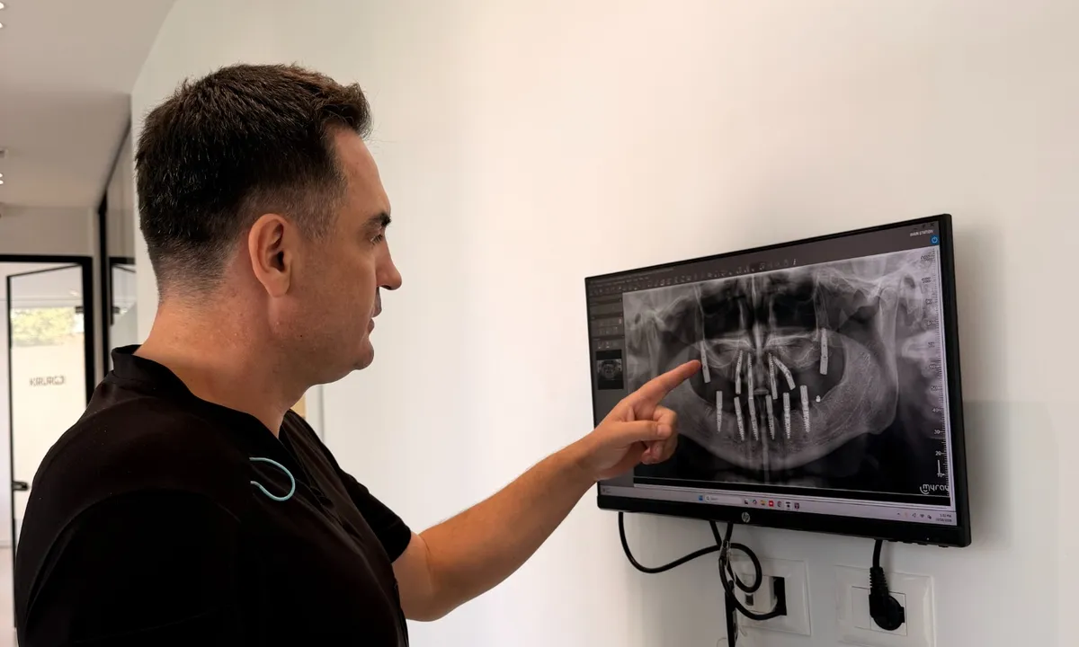A dentist discusses a panoramic X-ray showing dental implants. This is an illustrative photo; it does not, on its own, confirm that the implants shown are pterygoid implants.